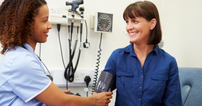 A healthcare professional checks a patient's blood pressure during a medical appointment in a doctor's examination room.
