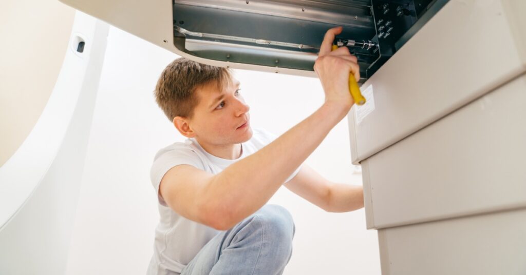 Medical Devices That Need Frequent Servicing 3 A technician uses a screwdriver to inspect an exposed mechanical compartment beneath a large piece of equipment.