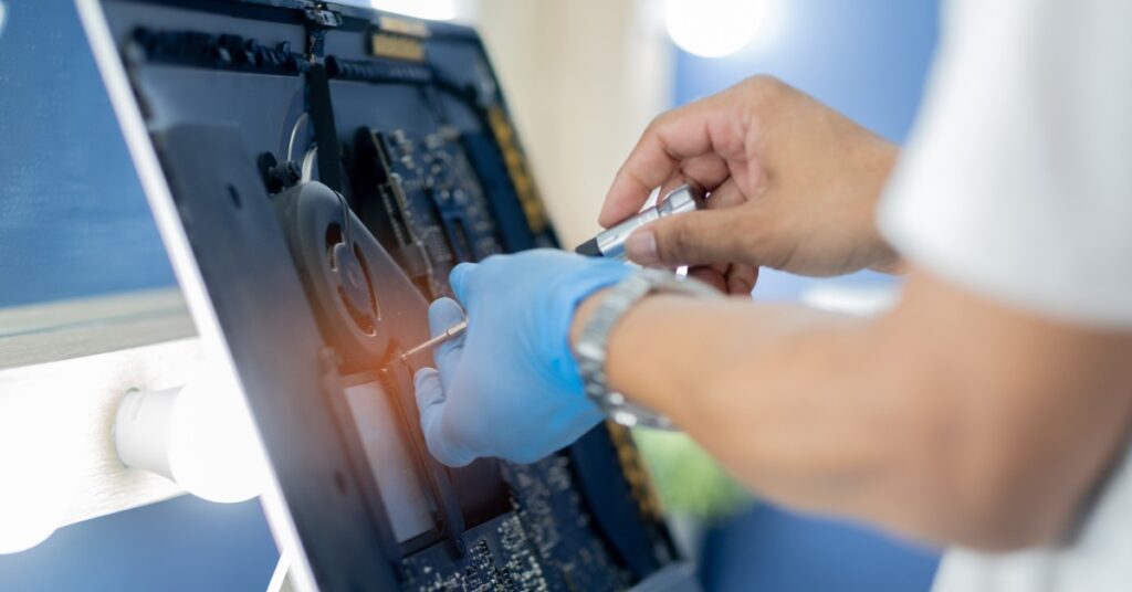 Medical Devices That Need Frequent Servicing 2 A technician wearing a protective glove uses a tool to inspect internal components of an opened monitor device.